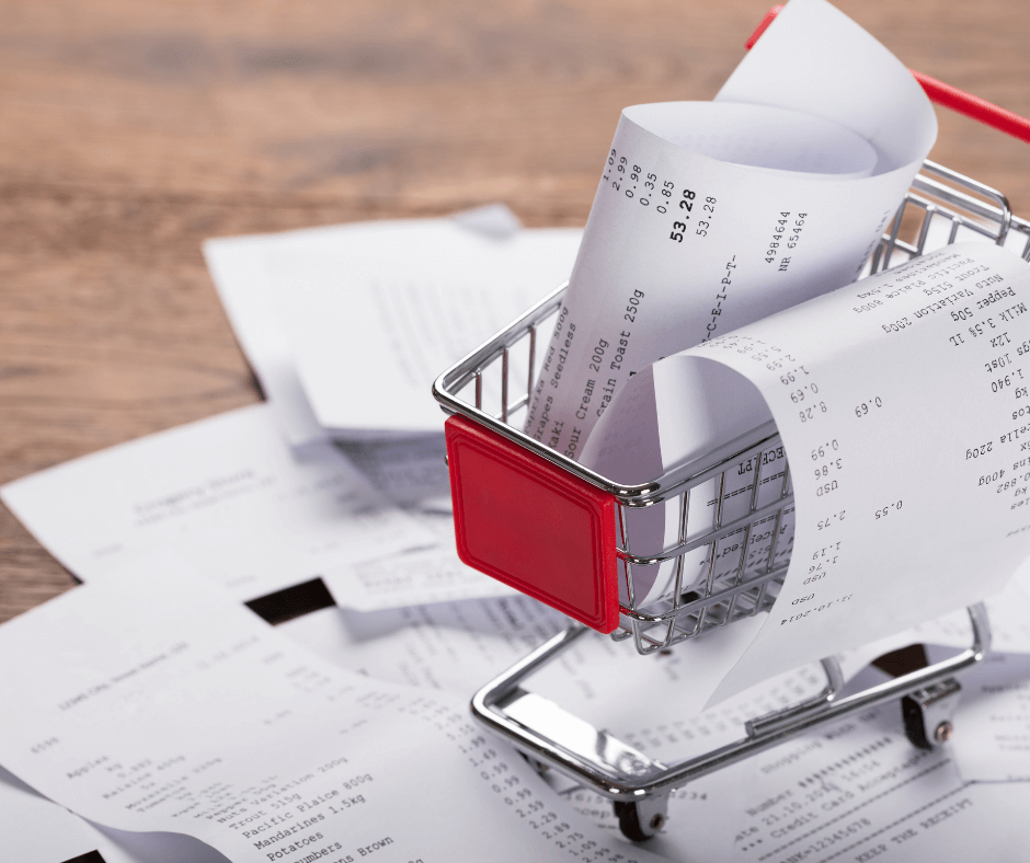 close up of a tiny shopping cart holding a curled up receipt